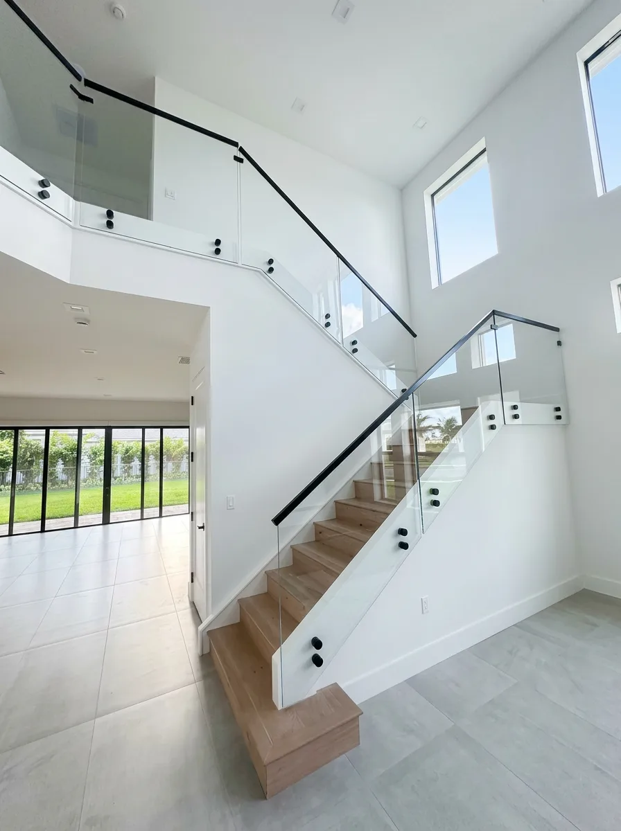 Two-story frameless glass stair railing with black standoffs and handrail